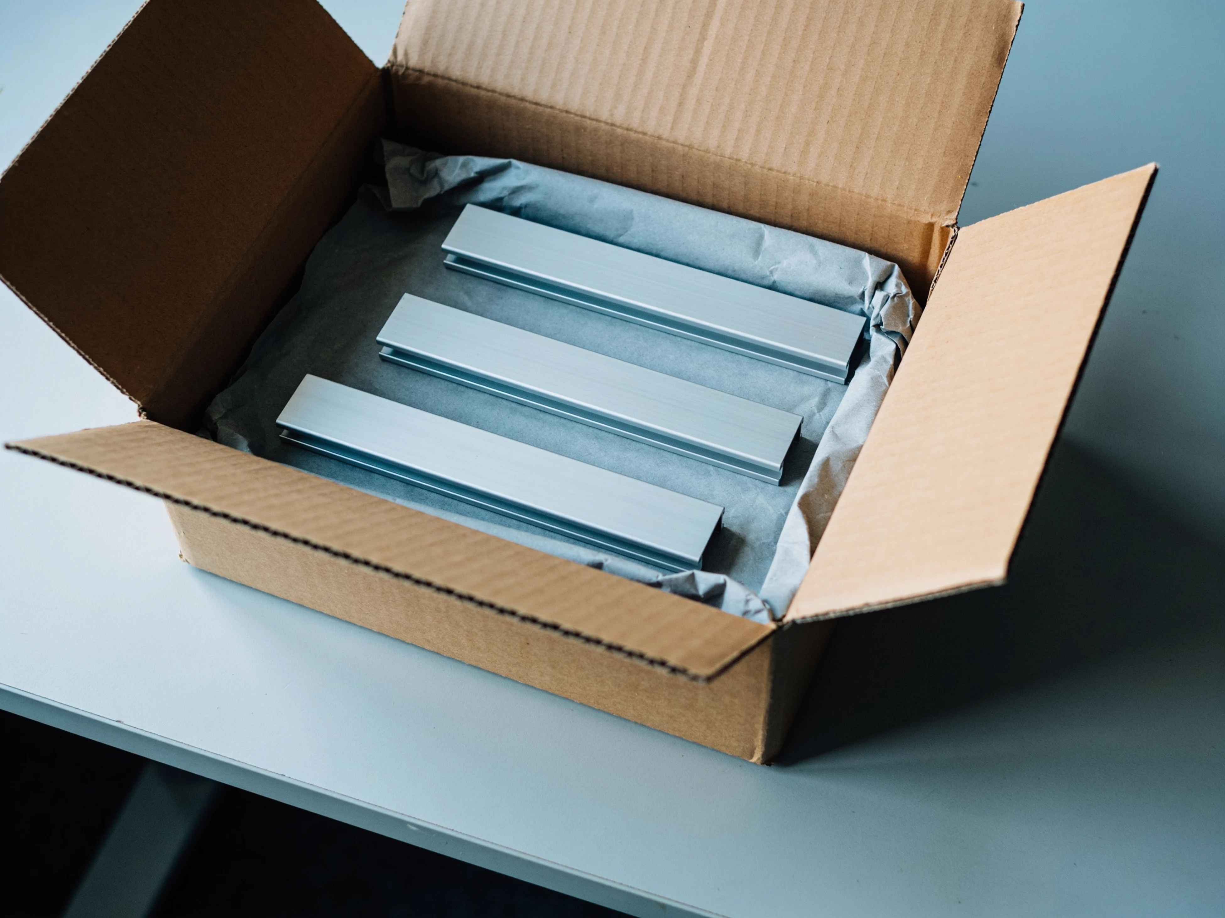 Offener Versandkarton mit Aluminiumprofilen in Packpapier